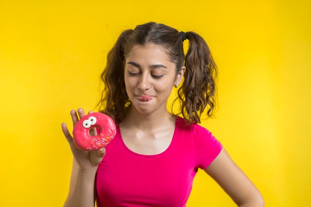 Foto una niña feliz le lamió la frente con un sabor de deliciosas donas.