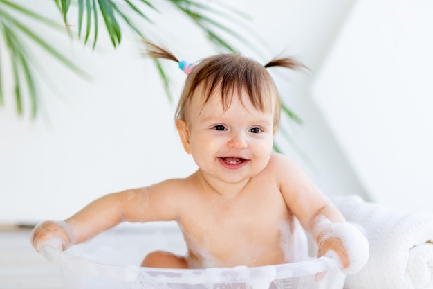 Niña feliz se lava y juega en un lavabo