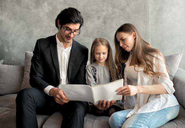 Niña feliz lee un libro con sus padres en casa