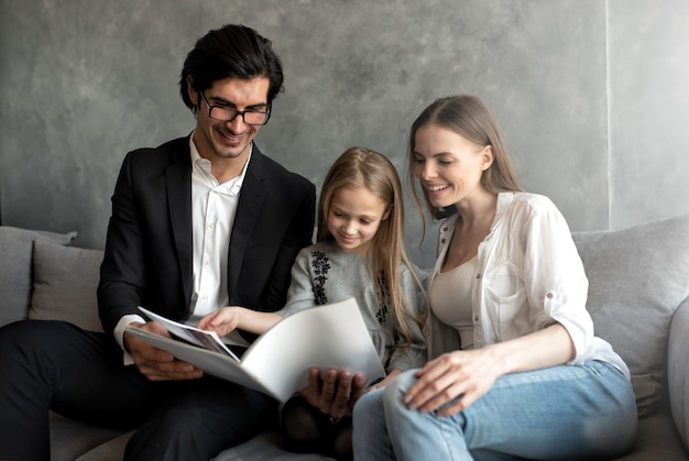 Niña feliz lee un libro con sus padres en casa