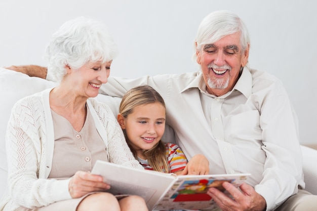 Niña feliz leyendo con abuelos