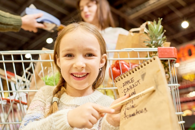 Niña feliz con lista de compras