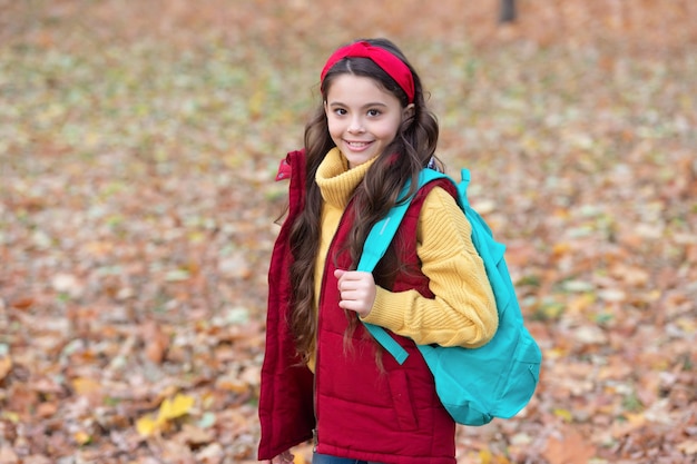 Niña feliz llevando la bolsa escolar en el día de otoño Niña adolescente de vuelta a la escuela 1 de septiembre Educación escolar Día del conocimiento