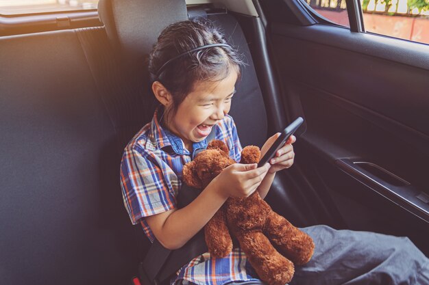 Niña feliz, llevando, cinturones de seguridad, en coche