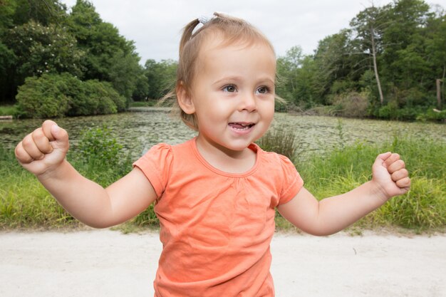 Niña feliz con las manos en el parque de verano