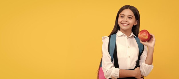 Niña feliz mantenga manzana y bolsa de la escuela conocimiento de fondo amarillo Banner de estudiante de la escuela Retrato de alumno de colegiala con espacio de copia