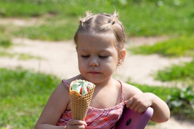 Niña feliz mirando el cuerno de gofre de helado en el parque de verano