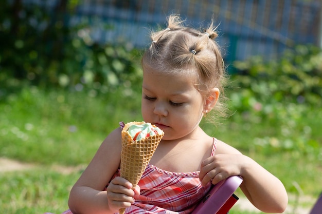 Niña feliz mirando el cuerno de gofre de helado en el parque de verano