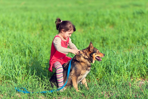 Niña feliz montando a su perro en el campo