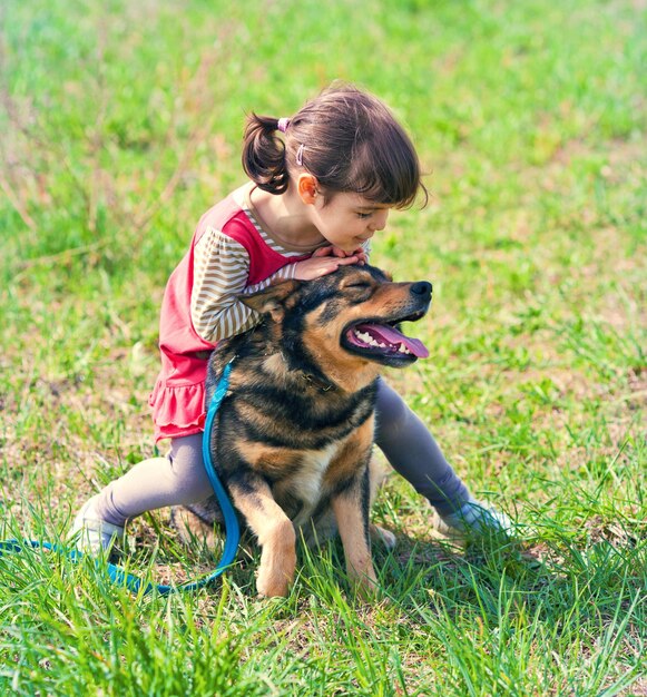 Niña feliz montando a su perro en el campo