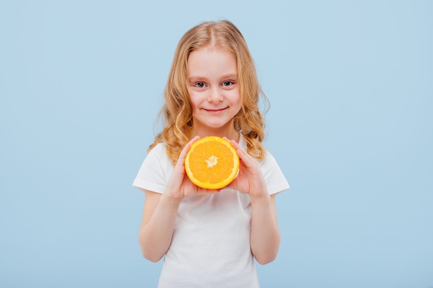 Niña feliz con una naranja en la mano