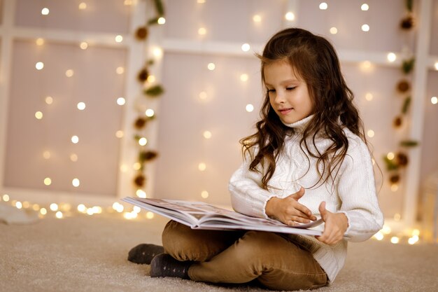 Niña feliz niño está leyendo un libro de cuento de hadas