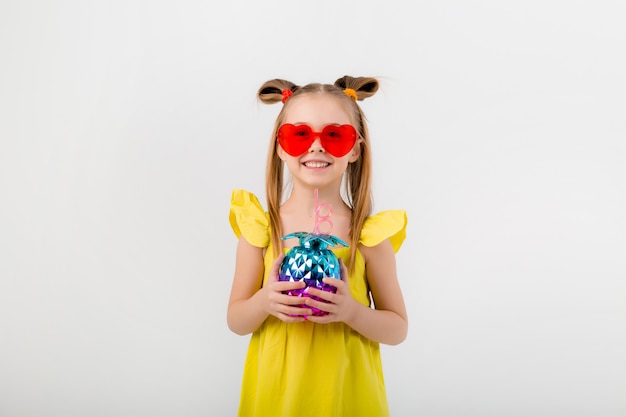 Niña feliz niño en gafas de sol sosteniendo un vaso con un cóctel aislar