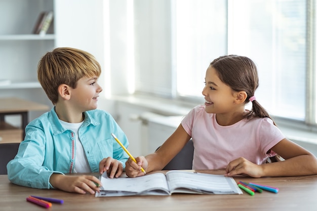 La niña feliz y un niño haciendo los deberes en el escritorio.