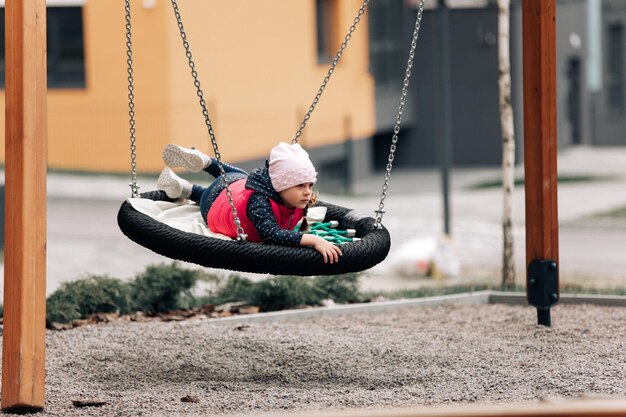 Niña feliz y niño jugando en la diapositiva niña en el patio de recreo