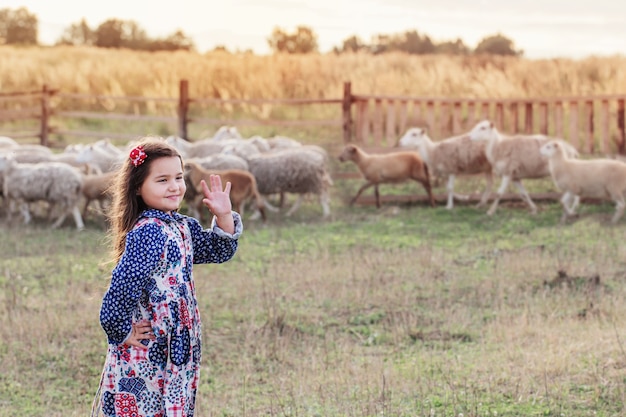 Niña feliz con ovejas en la granja