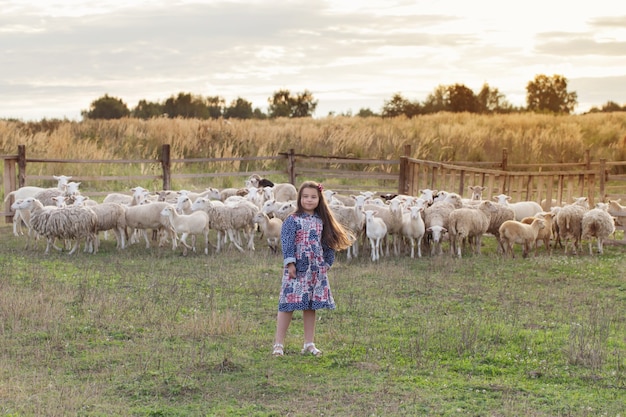 Foto niña feliz con ovejas en la granja