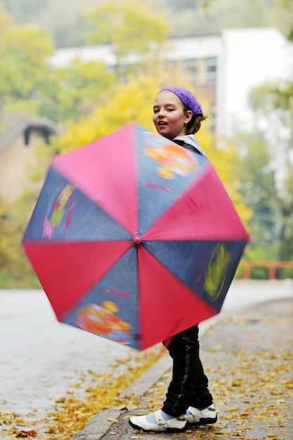 niña feliz con paraguas al aire libre en el parque en el día de lluvia de la temporada de otoño