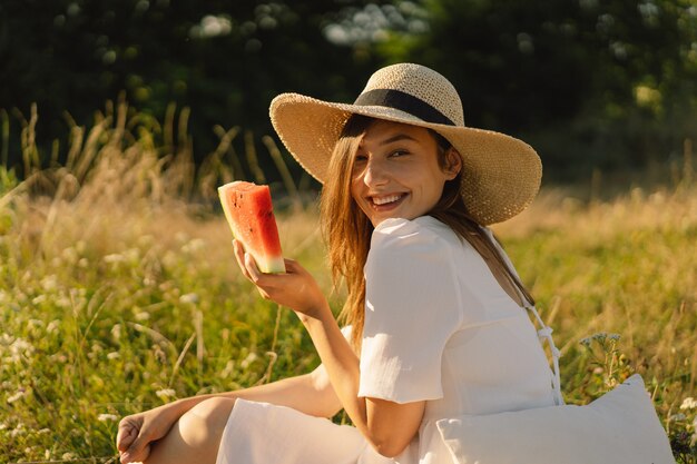 Niña feliz en el parque al aire libre con refrescante fruta de sandía mujer come un trozo de sandía