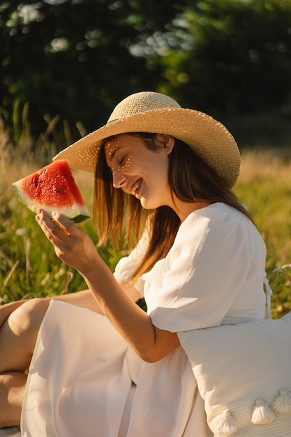 Niña feliz en el parque al aire libre con refrescante fruta de sandía mujer come un trozo de sandía