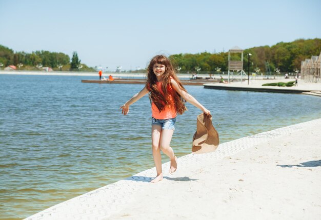 Una niña feliz con el pelo largo corre por la playa