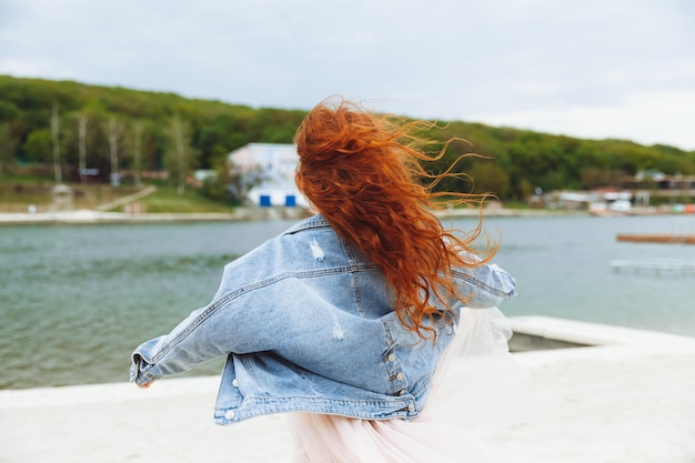 Niña feliz con el pelo rojo corre a lo largo de la playa niño en la playa