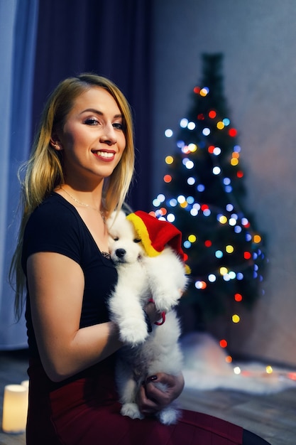Niña feliz con perro husky samoyedo en adornos navideños