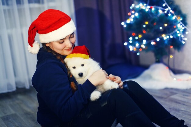 Niña feliz con perro husky samoyedo en adornos navideños