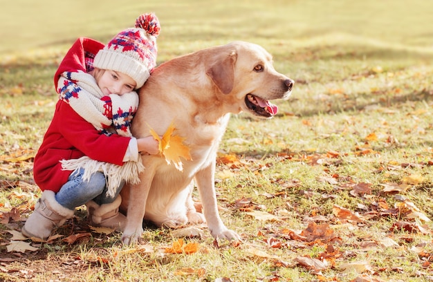 Niña feliz con perro en el parque otoño