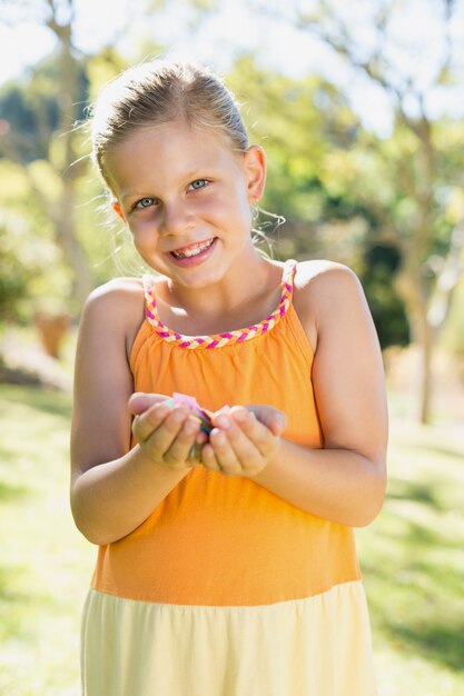 Niña feliz con pétalos en el parque