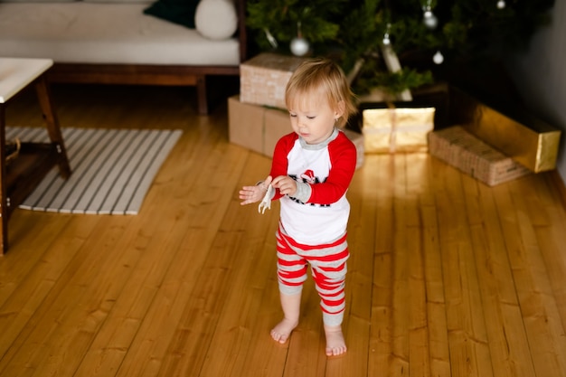 Niña feliz en pijama rojo y blanco con regalos de Navidad