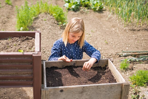 Niña feliz plantando semillas en el huerto