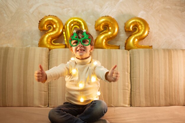 La niña feliz se pone las gafas de Año Nuevo con un árbol y se regocija en la Navidad. concepto de feliz navidad.