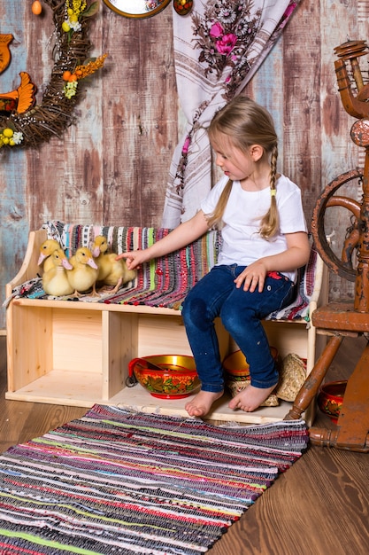 Niña feliz posando con lindos patitos de pascua esponjosos