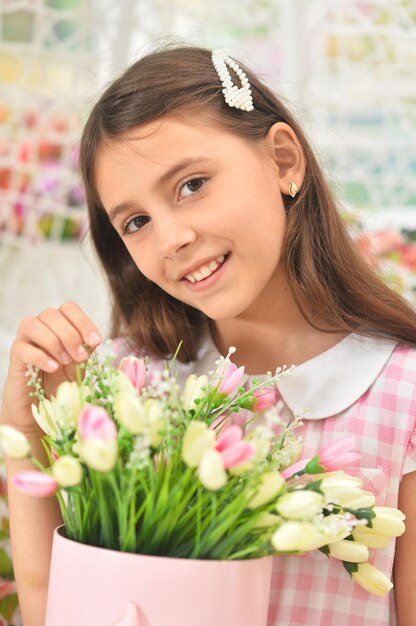 Niña feliz posando con tulipanes en columpio