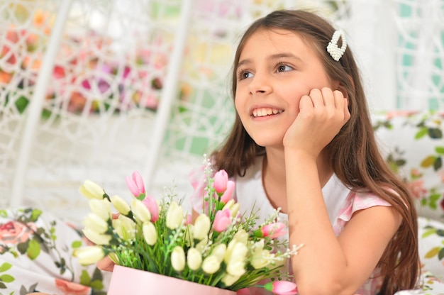 Niña feliz posando con tulipanes en columpio