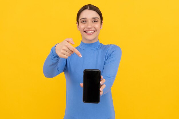 Foto niña feliz que señala el dedo en la pantalla del teléfono inteligente, copia espacio, presentación.