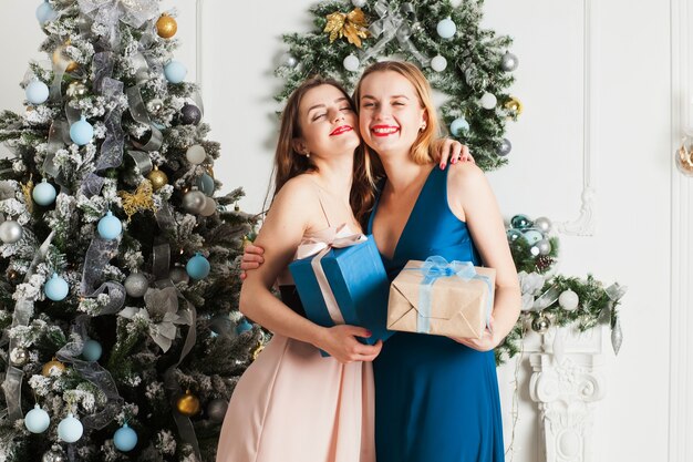 Niña feliz recibió un regalo de Navidad de su novia. Junto al árbol de Navidad.