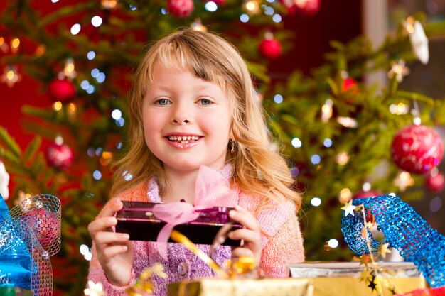 niña feliz con regalo de Navidad en Nochebuena