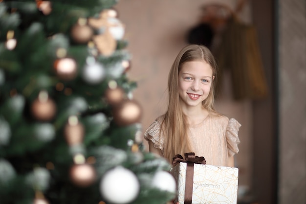 Niña feliz con regalo de Navidad de pie cerca del árbol de Navidad. concepto de vacaciones