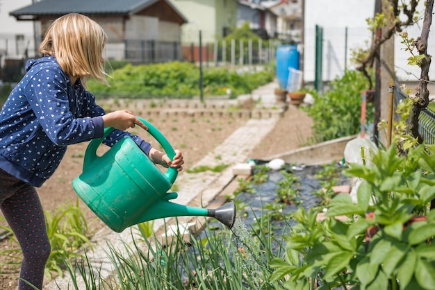 Niña feliz regando el huerto en primavera