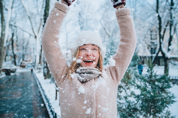 Niña feliz se ríe y arroja nieve sobre sí misma nieve en primer plano feliz navidad