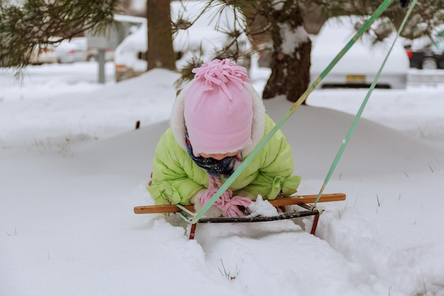Una niña feliz y risueña con una chaqueta morada y un gorro de punto blanco jugando y corriendo en un hermoso parque nevado de invierno el día de Navidad