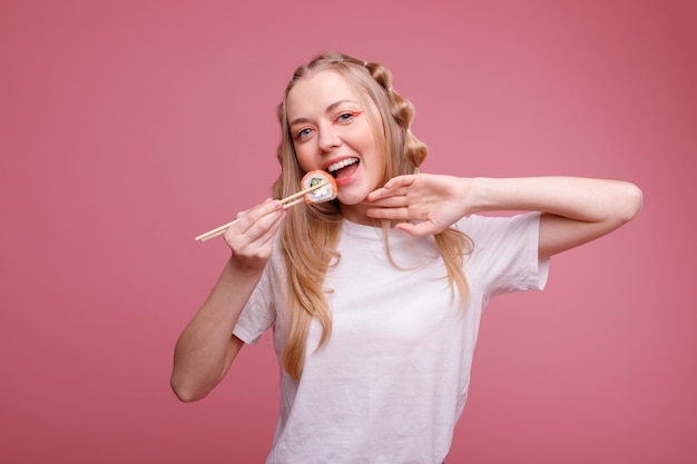 Niña feliz con rollos en superficie rosa