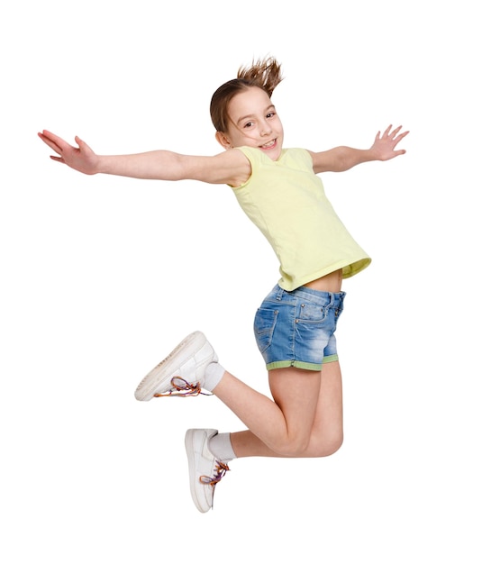 Niña feliz saltando sobre fondo blanco aislado. Adolescente en ropa casual de verano sonriendo y posando. Vida activa y concepto de infancia feliz.