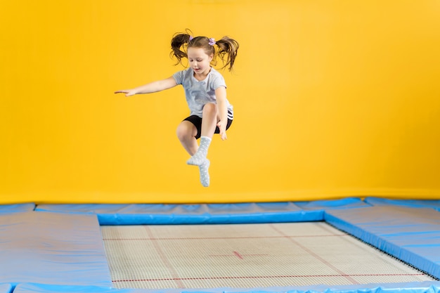 Niña feliz saltando en el trampolín en el gimnasio