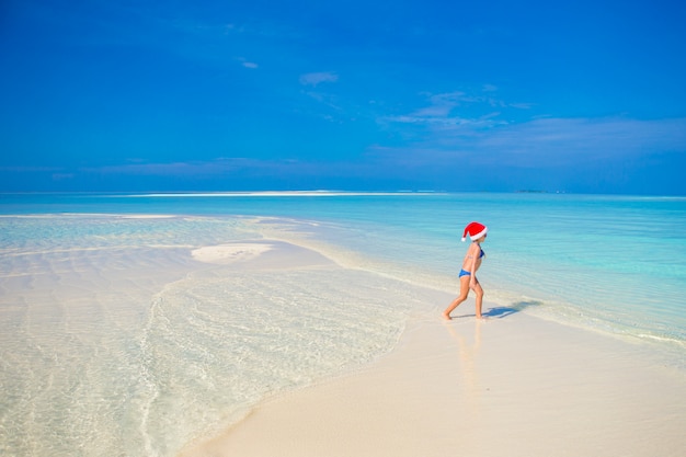 Niña feliz en Santa hat durante vacaciones en la playa en Maldivas