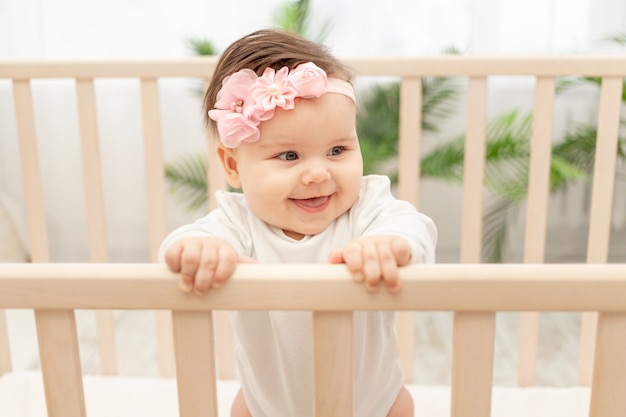 Niña feliz seis meses de pie en la cuna