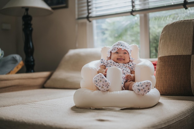 Niña feliz sentada en un asiento de bebé inflable