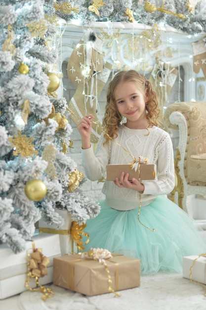 Niña feliz sentada con regalos en Navidad